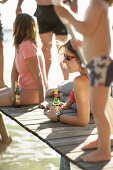 Zwei Frauen trinken Bier auf einem Holzsteg am Wörthsee, Bayern, Deutschland, MR