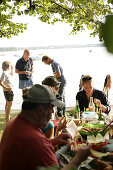 People having barbecue dinner on the lakeshore, Woerthsee, Upper Bavaria, Bavaria, Germany