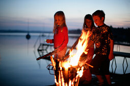 Kinder stehen an einem Lagerfeuer, Wörthsee, Bayern, Deutschland, MR