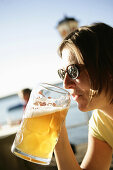 Mid adult woman drinking beer, beer garden of the restaurant Woerl, Woerthsee, Bavaria, Germany, MR