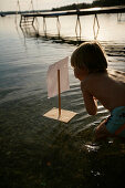 Junge spielt mit einem Floß im Wörtsee, Bayern, Deutschland, MR