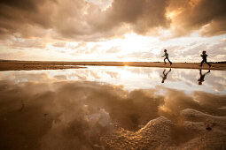 Zwei Kinder laufen am Strand, Spiegelung von Wolkenhimmel im Wasser, Segeltorpstrandet, Halmstadt, Skane, Schweden