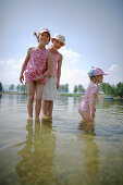 Three girls (3-8 years) standing in water, Lake Staffelsee, Upper Bavaria, Germany
