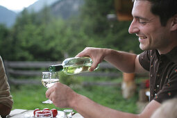 Man pouring wine into glass, National Park Hohe tauern, Kärnten, Austria