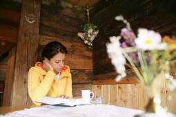 Frau liest ein Buch in einer Almhütte, Heiligenblut, Nationalpark Hohe Tauern, Kärnten, Österreich