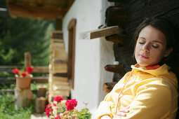 Frau sitzt mit geschlossenen Augen vor einer Almhütte, Heiligenblut, Nationalpark Hohe Tauern, Kärnten, Österreich