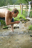 Man refreshing at a mountain stream, Heiligenblut, Hohe Tauern National Park, Carinthia, Austria