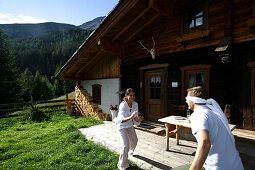 Couple playing blindman's buff beside alp lodge, Heiligenblut, Hohe Tauern National Park, Carinthia, Austria