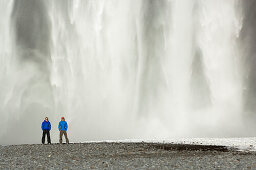 Two men in front of Skogarfoss waterfall, Iceland