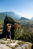 Climber on summit throwing a rope, Arco, Trentino-Alto Adige/Südtirol, Italy