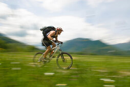 Mountainbiker fährt über Wiese, Nationalpark Triglav, Slowenien
