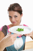 Mid adult woman holding a plate with peas, Styria, Austria