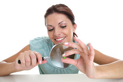 Woman observing pea with magnifying glass, Styria, Austria