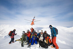 Group of skiers in snow, helicopter in background, Heliskiing, Kamchatka Peninsula, Sibiria, Russia