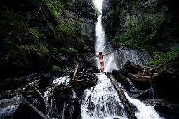 Naked young man standing in front of a waterfall, See, Tyrol, Austria