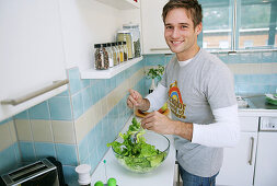 Junger Mann bereitet einen Salat zu, München, Deutschland