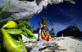 Frau sitzt am Strand und betrachtet den Aussicht, Navadra Island, Mamanuca Gruppe, Fidschi, Südsee