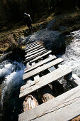 Hiker behind bridge over Knuttenbach Creek, Knuttenbachtal Valley near Brunico, Alto Adige, Italy