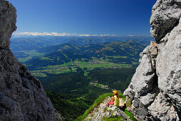 Hiker resting at Kleines Toerl, view to the valley of Ellmau and Going, Kaiser range, Tyrol, Austria