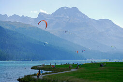 Kite surfer, pedestrians and cyclists at lake Silvaplaner, Upper Engadin, Grisons, Switzerland