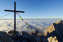 Summit cross with prayer flags on mountain Ellmauer Halt, Kaiser range, Tyrol, Austria