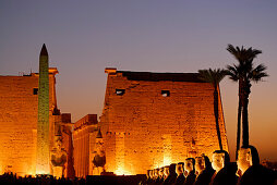sphinxes and obelisk in front of first pylon in Luxor temple, illuminated in twilight, Egypt, Africa