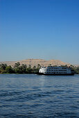 Kreuzfahrtschiff auf dem Nil und Palmen am Westufer, Luxor, Ägypten, Afrika