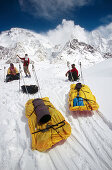 Skiers hauling sleds under Broad Peak, Godwin-Austen glacier. Karakoram mountains, Pakistan