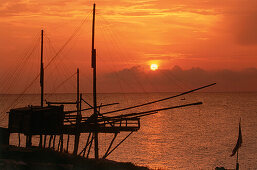 Silouette of a fishing net frame at sunrise, Trabucco, Punta Lunga near Vieste, Gargano, Apulia, Italy