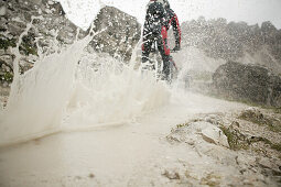 Mountain biker passing watercourse, Tre Cime di Lavaredo, Dolomites, Veneto, Italy