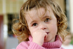 Three year old girl , looking very pensive and worried, at nursrey school