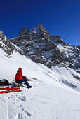 young woman resting during ascent of Kreuzkopf with view to summit of Hochvogel, Allgaeu range, Allgaeu, Tyrol, Austria