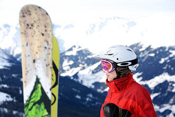 Eine Person mit Snowboards vor verschneiten Bergen, Skigebiet Paznaun, Tirol, Österreich