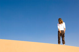 Woman inspecting, looking at a sand dune, desert, United Arab Emirates