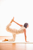 Mid adult woman practising yoga (Cat Pose), yoga studio at Linz, Austria