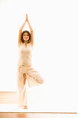 Frau mittleren Alters macht Yoga (Baumstand), Yogastudio in Linz, Österreich