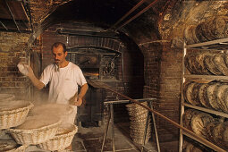 Baker baking bread in the bakery, wood-fired oven, Boulangerie in Saint Germain des Pres, Paris, France