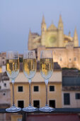 Drei Gläser mit Cava Sekt vor beleuchteter Kathedrale La Seu, Blick von Dachterrasse des Hotel Tres, Palma, Mallorca, Balearen, Spanien, Europa