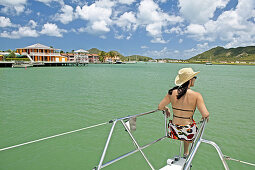 Woman sitting on the front of a catamaran, sailing in Antigua