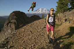 A man jumps off a rock while hiking on a trail near Mount Adams. Washington. USA
