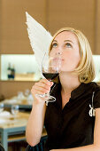 Engel, junge Frau mit Engelsflügeln trinkt ein Glass Rotwein, Restaurant, München, Bayern, Deutschland