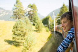 Junge Frau schaut aus einem Fenster von einem fahrenem Zug
