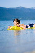 Young woman on airbed on lake Walchensee, Bavaria, Germany