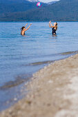 Two young women playing with a ball in lake Walchensee, Bavaria, Germany