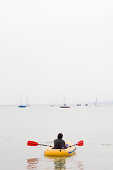 Young man in a rubber dingy, Lake Ammersee, Bavaria, Germany