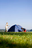 Children putting up tent on meadow