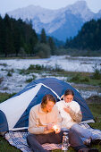 Young couple near a tent, man lighting a lantern, Lenggries, Upper Bavaria, Bavaria, Germany