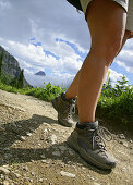 Female hikers legs on Highline Trail with Reynolds Peak in background, Glacier National Park, Montana, USA