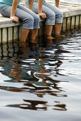 girl 13 girl 18 sitting on dock together with feet in lake