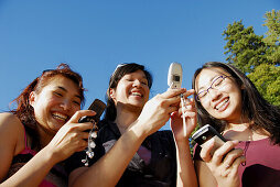 3 asian women each using cell phones